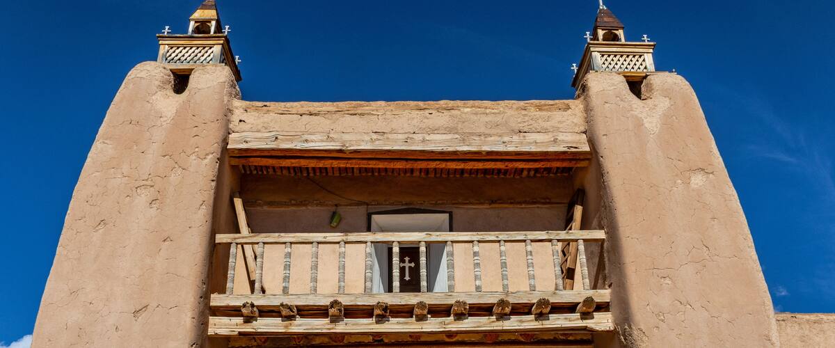 Un bâtiment doté d’un balcon, d’une porte en bois et de deux tours surmontées de croix.