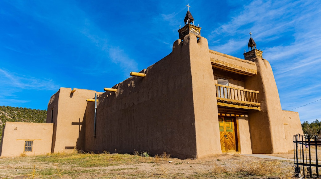 A traditional adobe church with a wooden balcony and a bell tower.