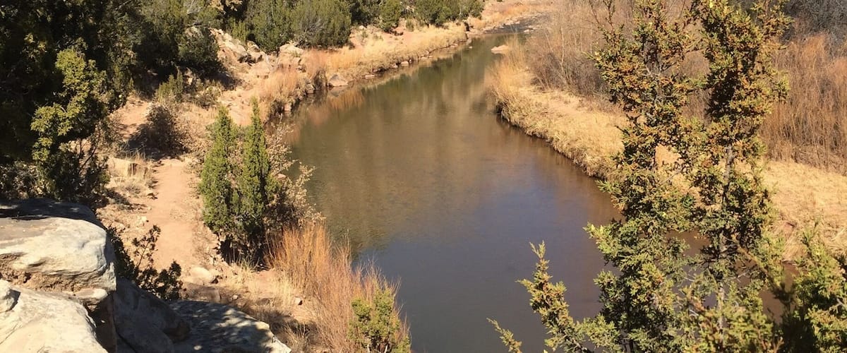 A river winding through a rocky canyon with sparse vegetation and a clear blue sky.