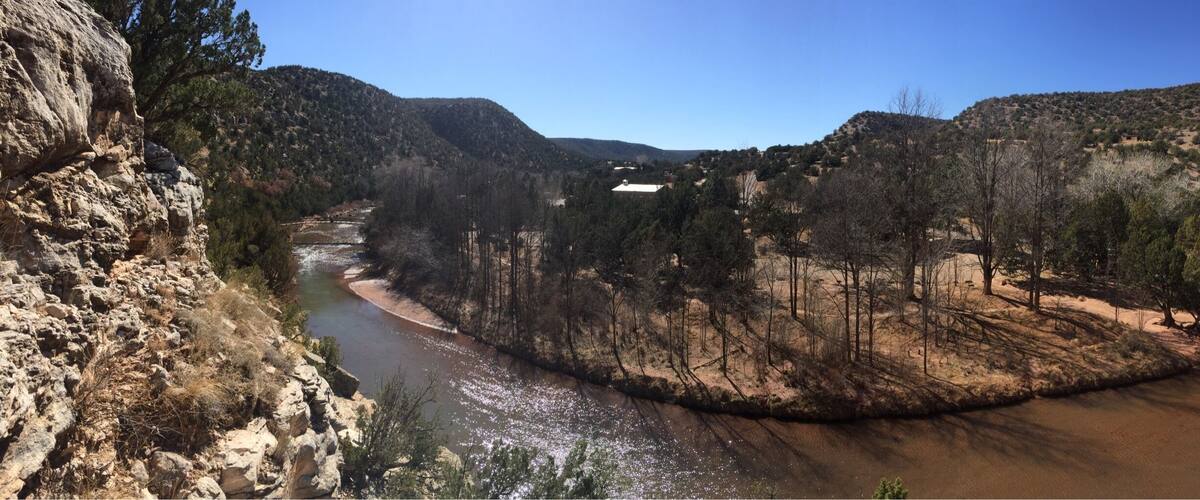 A river flowing through a canyon with rocky cliffs and sparse vegetation.
