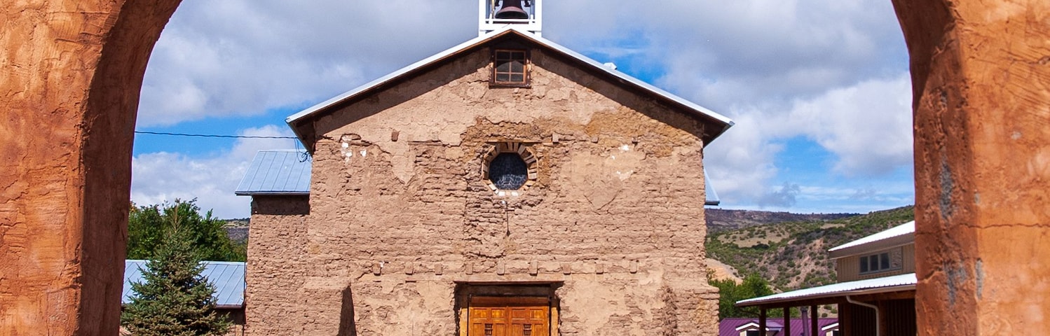 Una iglesia con un gran arco, una torre de campanas y una cruz en la parte superior.
