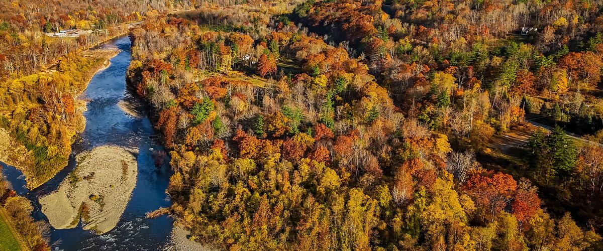 A river winding through a forested valley with autumn foliage.