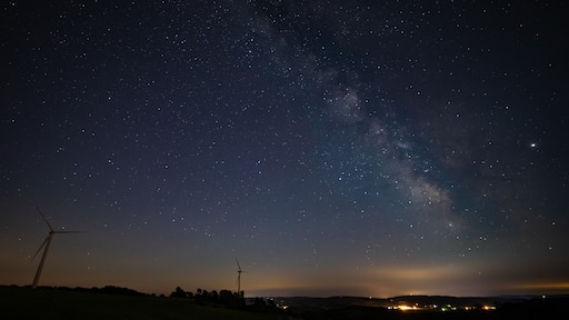 Milky Way photographed on clear sky night near a wind farm