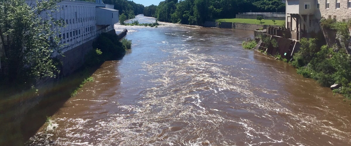 A river flowing through a town with industrial buildings and a bridge.