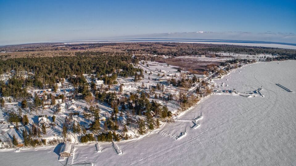 A snowy landscape with a town, dense forests, and a frozen lake.