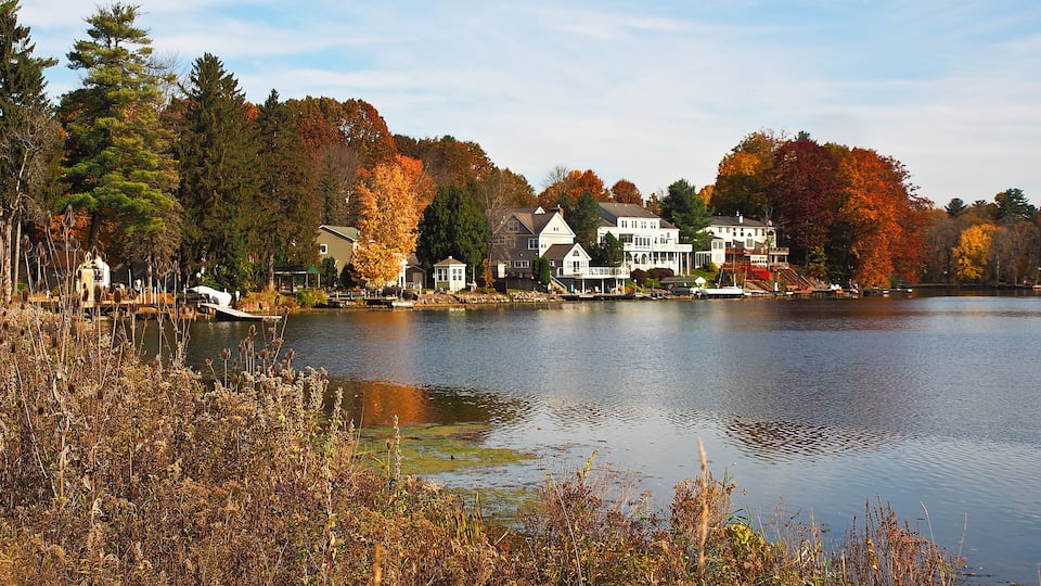 A lake surrounded by houses and autumn-colored trees.