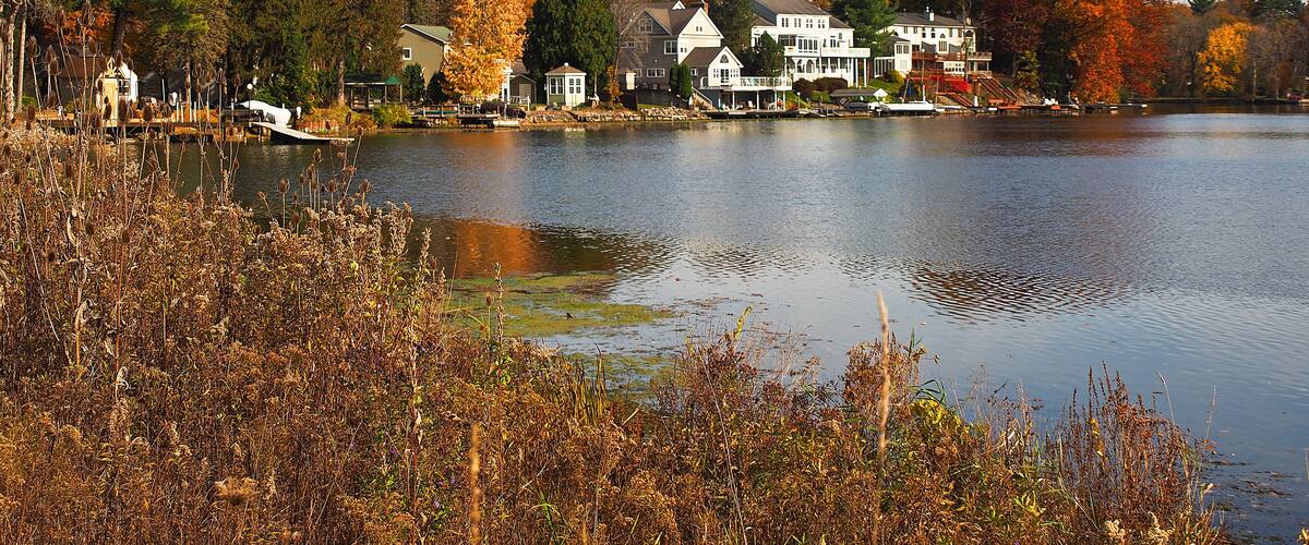 A lake surrounded by houses and autumn-colored trees.