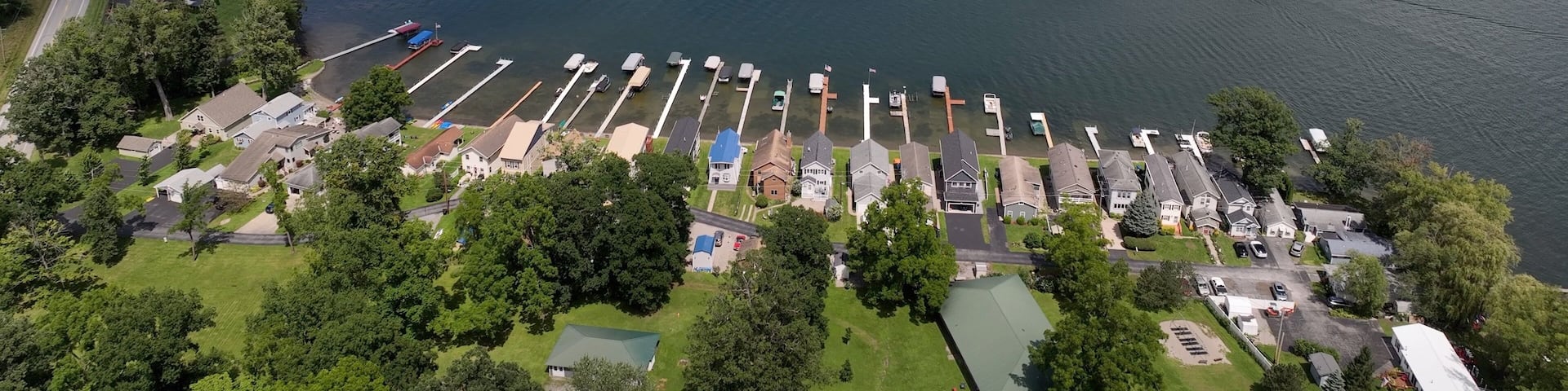 Conesus Finger Lake in New York State in summer with boaters, vacation homes enjoying a day by the lake on a beautiful day with blue sky and clouds