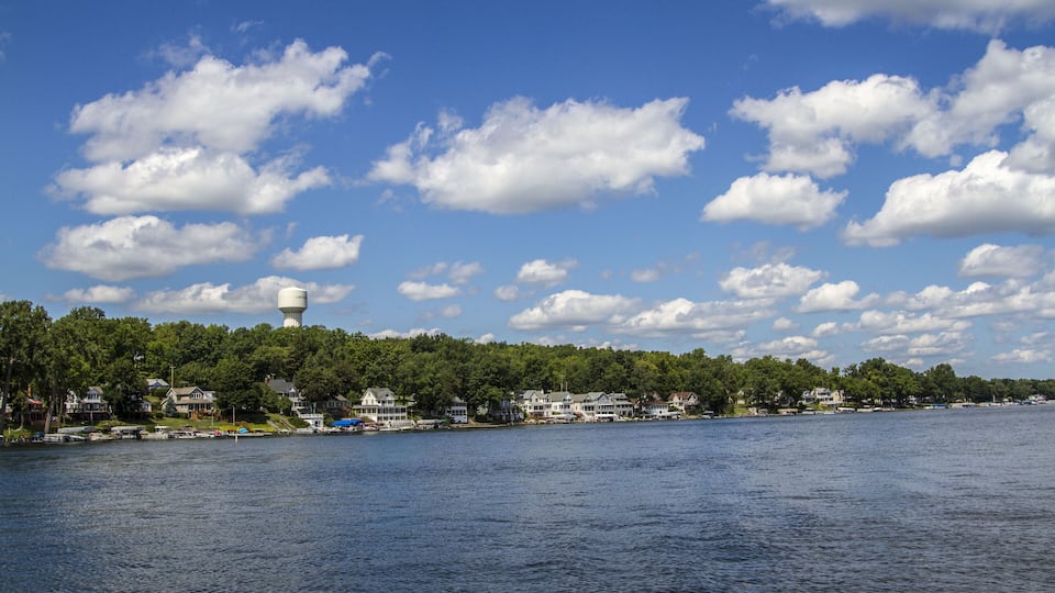 A lake with houses along the shore and a water tower on a hill.