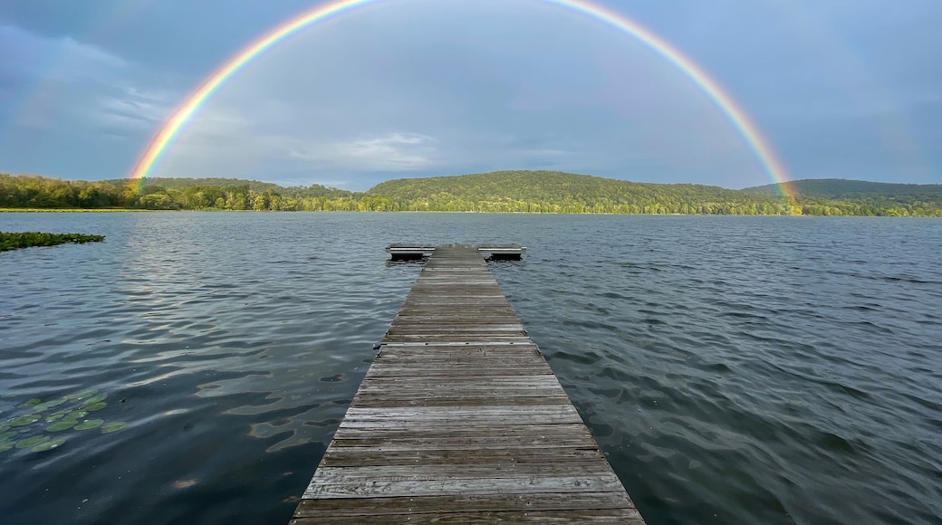 Congers, NY - USA - August 8, 2021: Landscape view of a rainbow over Rockland Lake in Rockland Lake State Park during the golden hour.