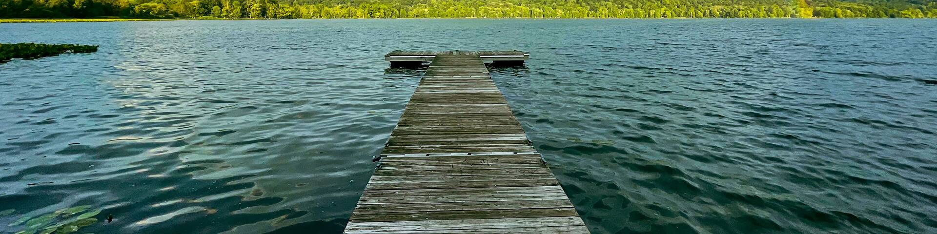 Congers, NY - USA - August 8, 2021: Landscape view of a rainbow over Rockland Lake in Rockland Lake State Park during the golden hour.