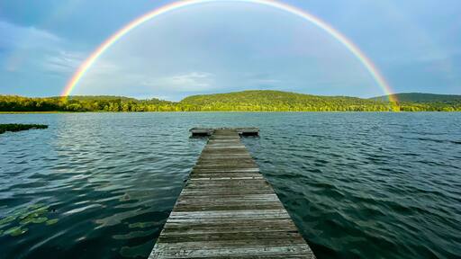 Congers, NY - USA - August 8, 2021: Landscape view of a rainbow over Rockland Lake in Rockland Lake State Park during the golden hour.