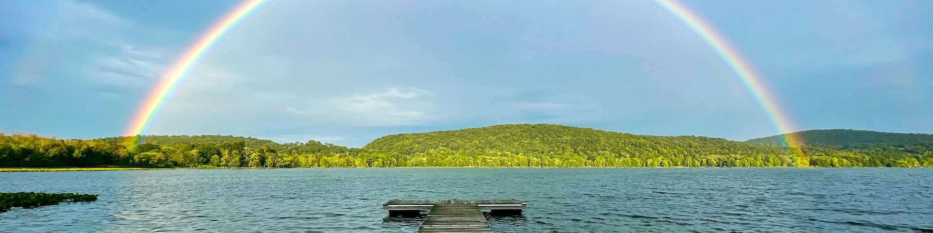 Congers, NY - USA - August 8, 2021: Landscape view of a rainbow over Rockland Lake in Rockland Lake State Park during the golden hour.