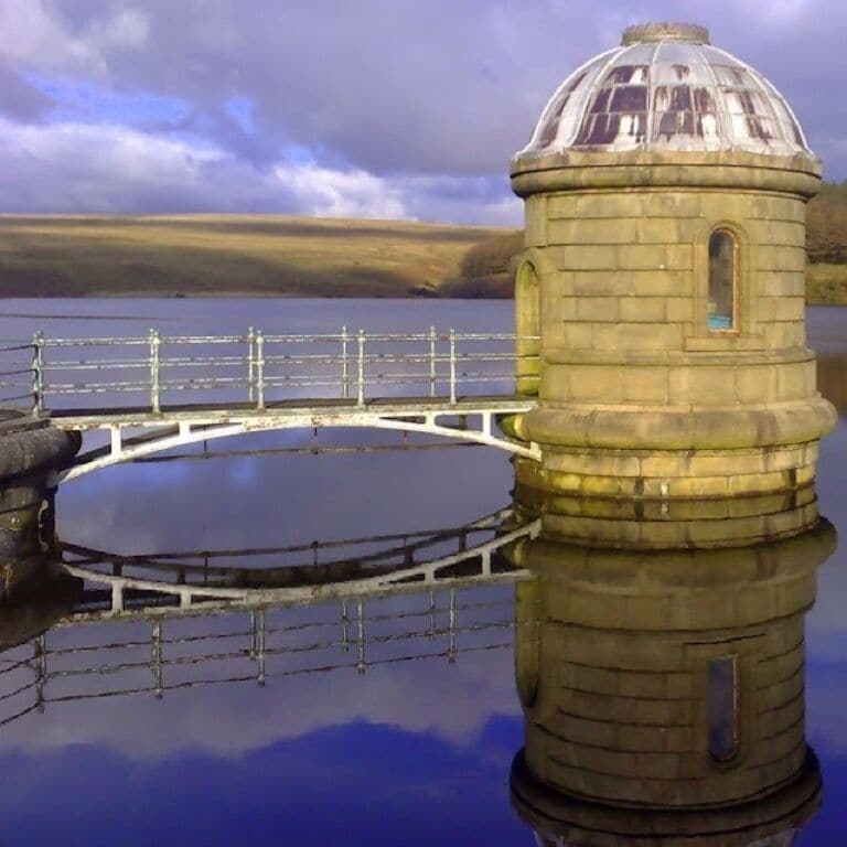 A stone tower with a dome, a circular bridge, and a calm lake.
