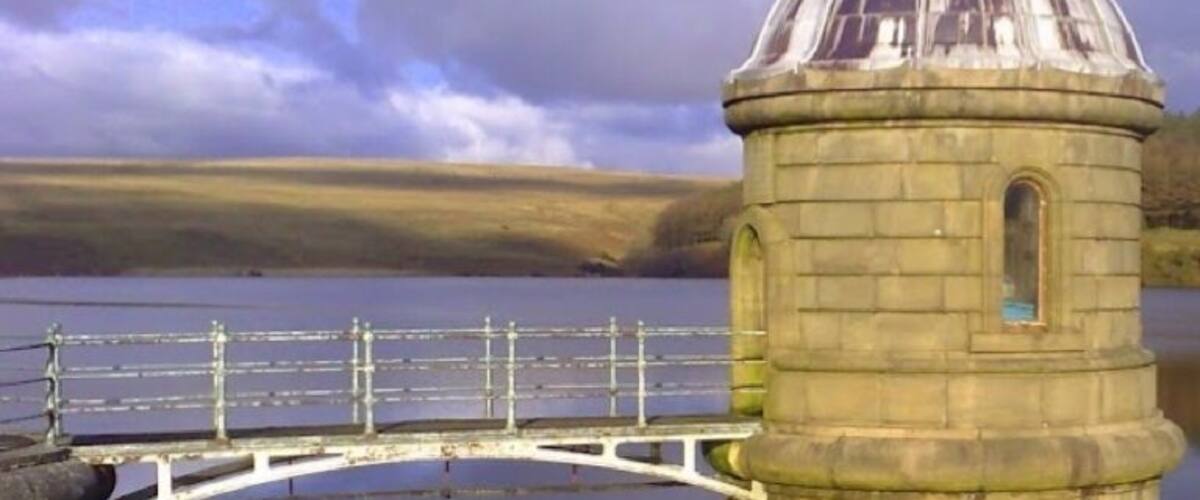 A stone tower with a dome, a circular bridge, and a calm lake.