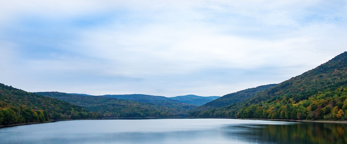 A calm lake surrounded by forested hills.