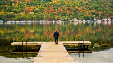 Man walking on swimming/fishing dock on Seneca Lake in the Finger Lakes Region of Upper New York near Dresden. Autumn color reflected in the lake.