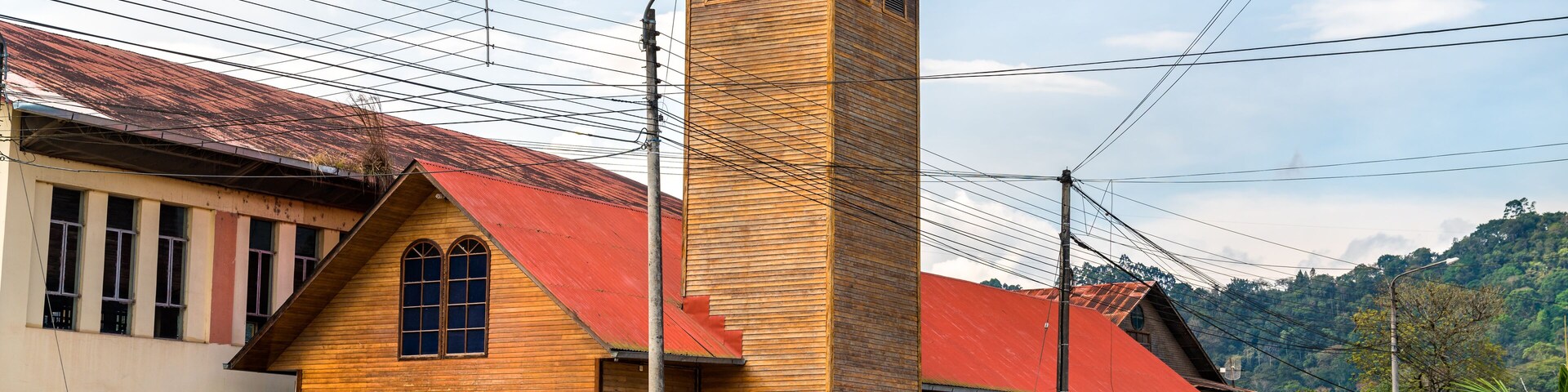 A wooden church with a red roof and a bell tower.