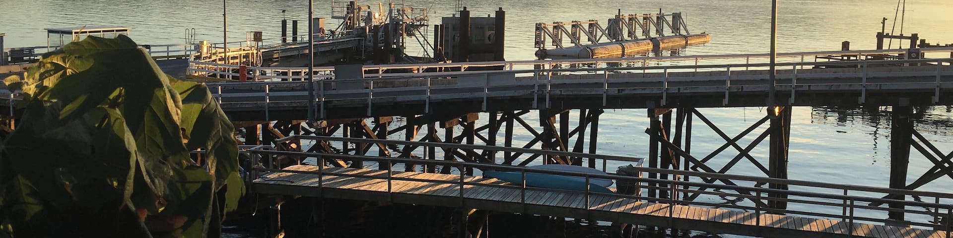 A pier extending into calm water with mountains in the background.