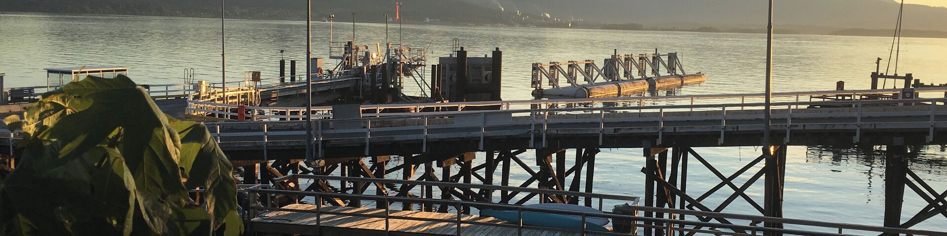 A pier extending into calm water with mountains in the background.