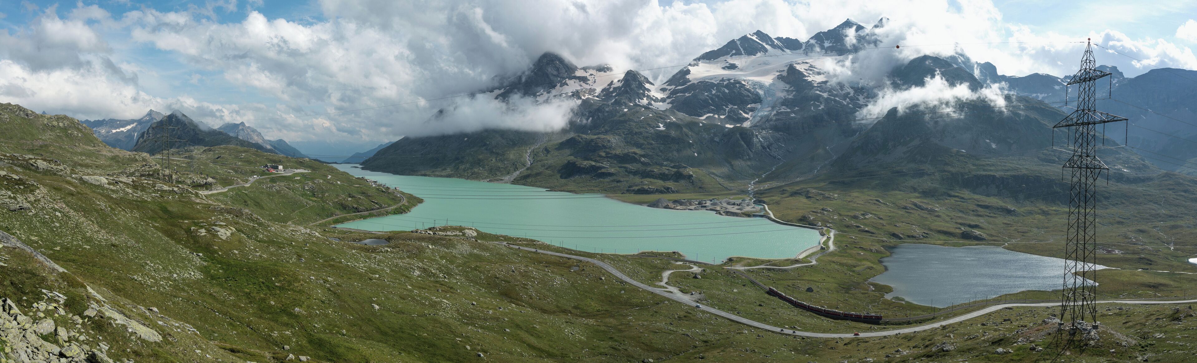 Lago Bianco - Gesamtansicht mit Lej Nair vom Hang unterhalb vom Piz Lagalb. Schön sieht man die namensgebenden Farben der Seen. Vor der Nord-Staumauer der Berninaexpress. Hinter dem See in der Mitte etwas eingehüllt Sassal Mason, nach rechts: die Carallücke und der Cambrenagletscher. Darüber Piz Caral und Piz Cambrena mit dem Gipfelfirn, der zum Piz Palü hinüber führt.