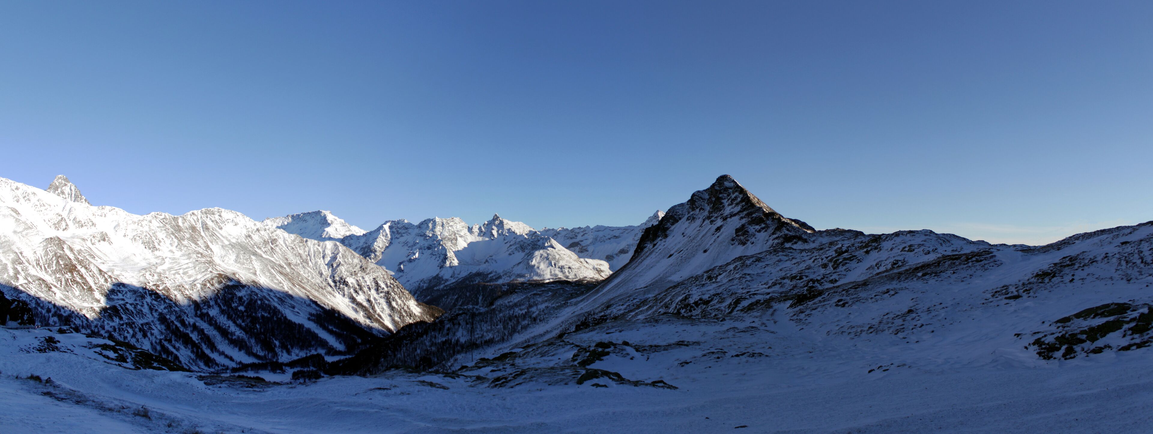 A snow-covered mountain range with sharp peaks and a clear blue sky.