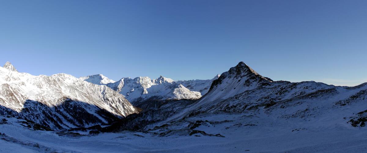 A snow-covered mountain range with sharp peaks and a clear blue sky.