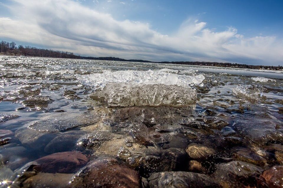 A frozen river with ice chunks and clear water.