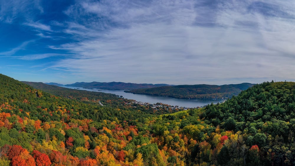 A mountainous landscape with a lake, autumn foliage, and a winding road.