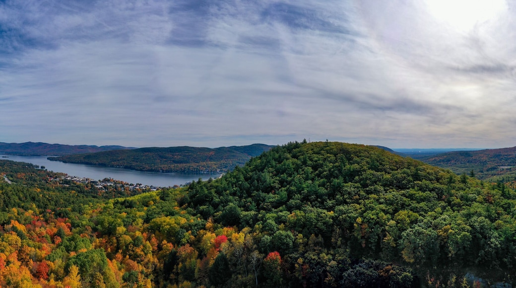 A mountainous landscape with a lake, autumn foliage, and a winding road.