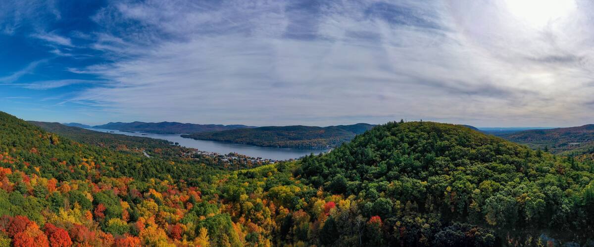 A mountainous landscape with a lake, autumn foliage, and a winding road.