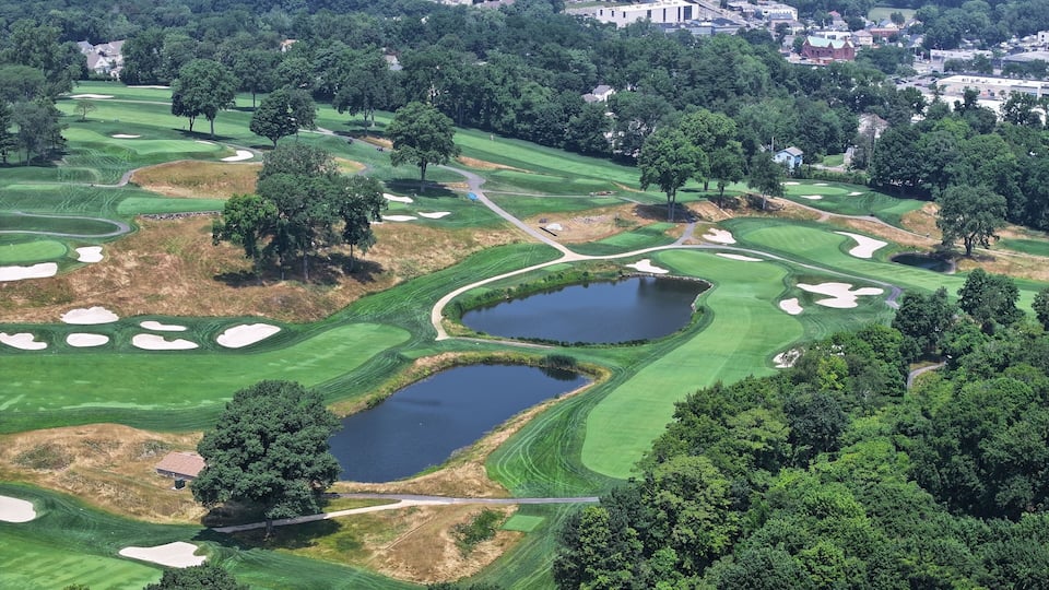A golf course with sand bunkers, water hazards, and a pond.