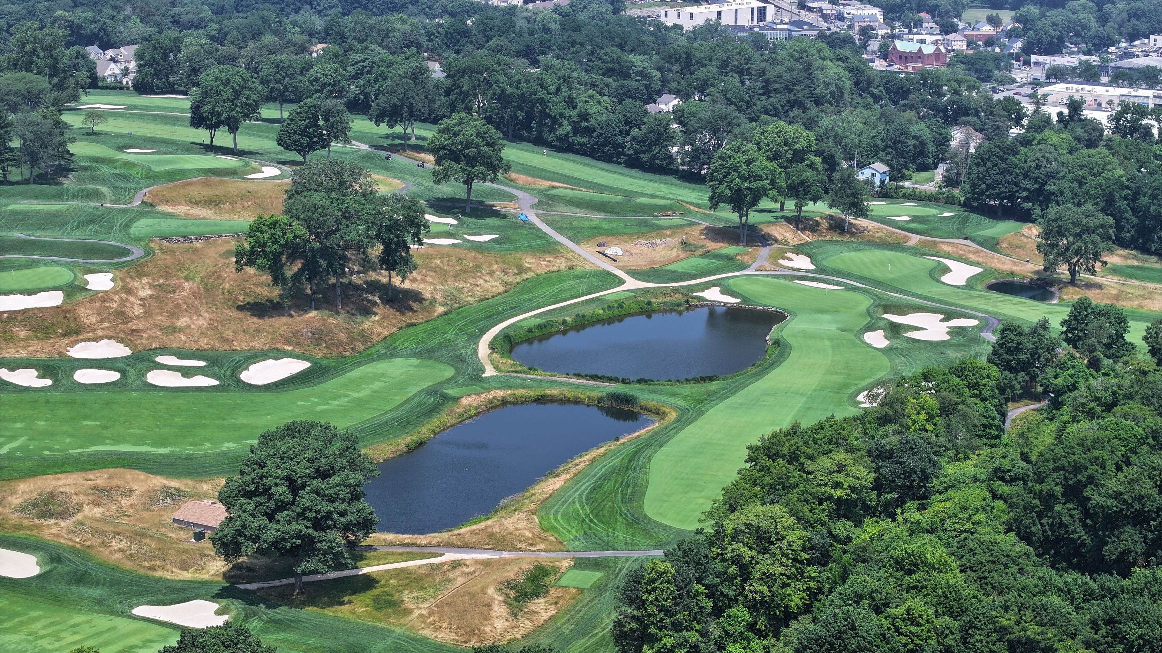 A golf course with sand bunkers, water hazards, and a pond.