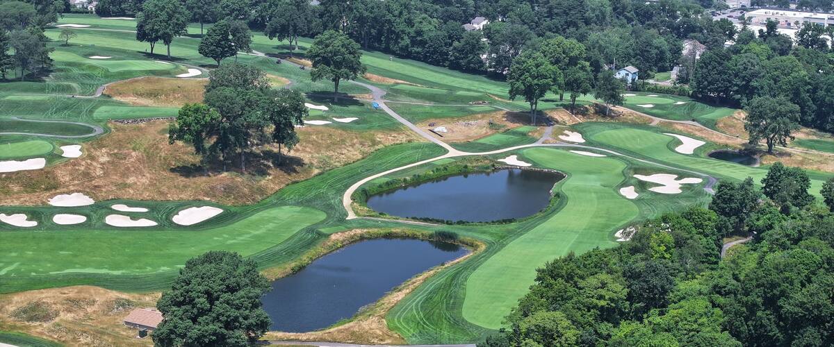 A golf course with sand bunkers, water hazards, and a pond.