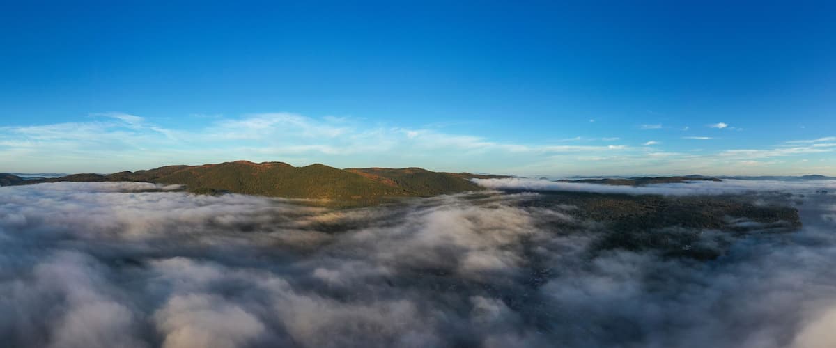 Cordillera montañosa sobre un mar de nubes, con cielo azul despejado.