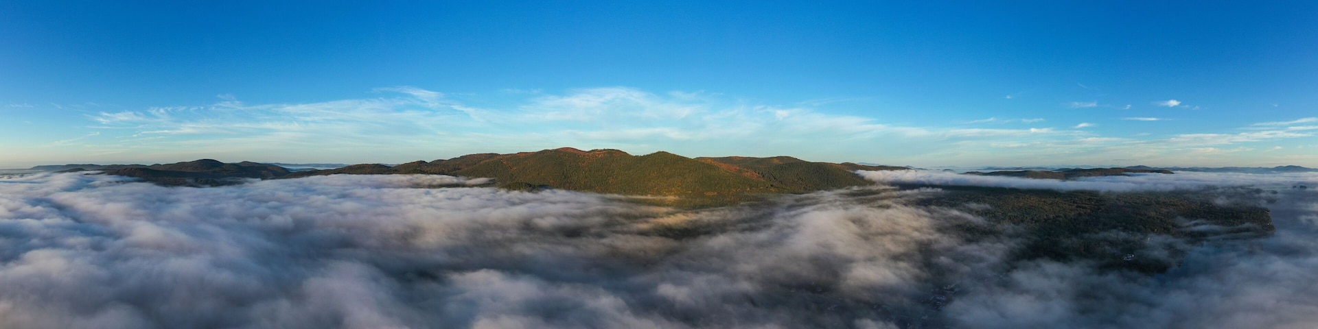 Cordillera montañosa sobre un mar de nubes, con cielo azul despejado.
