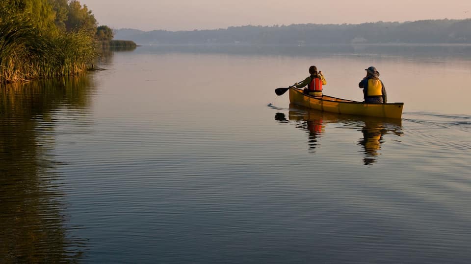 Young couple canoeing in Irondequoit Bay, Rochester, New York, USA.