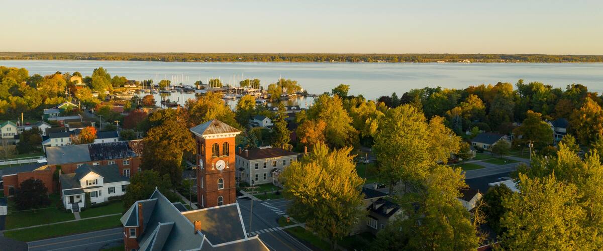 A town with a prominent clock tower, a lake, and autumn foliage.