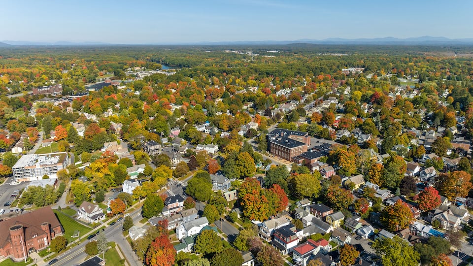 A residential area with autumn foliage, a large brick building, and a distant mountain range.