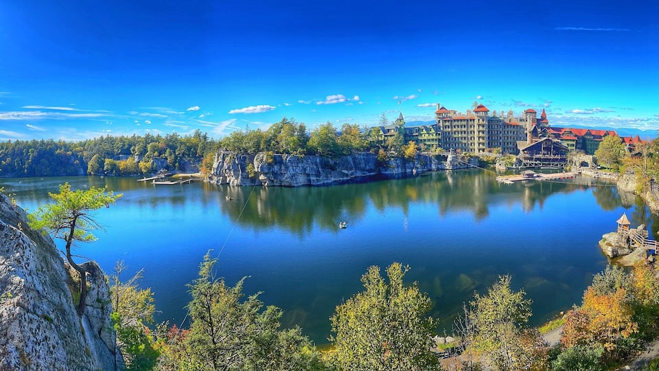 A lake surrounded by forest and historic buildings.