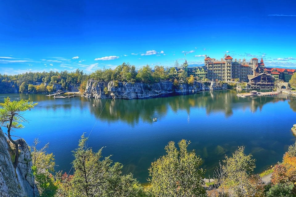 A lake surrounded by forest and historic buildings.