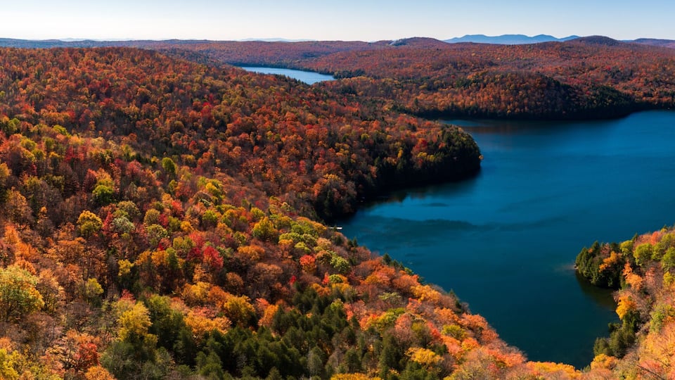 A mountainous landscape with a lake surrounded by autumn-colored trees.