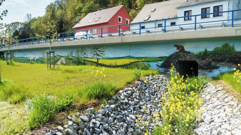 A bridge with a mural, a red house, and a white building.