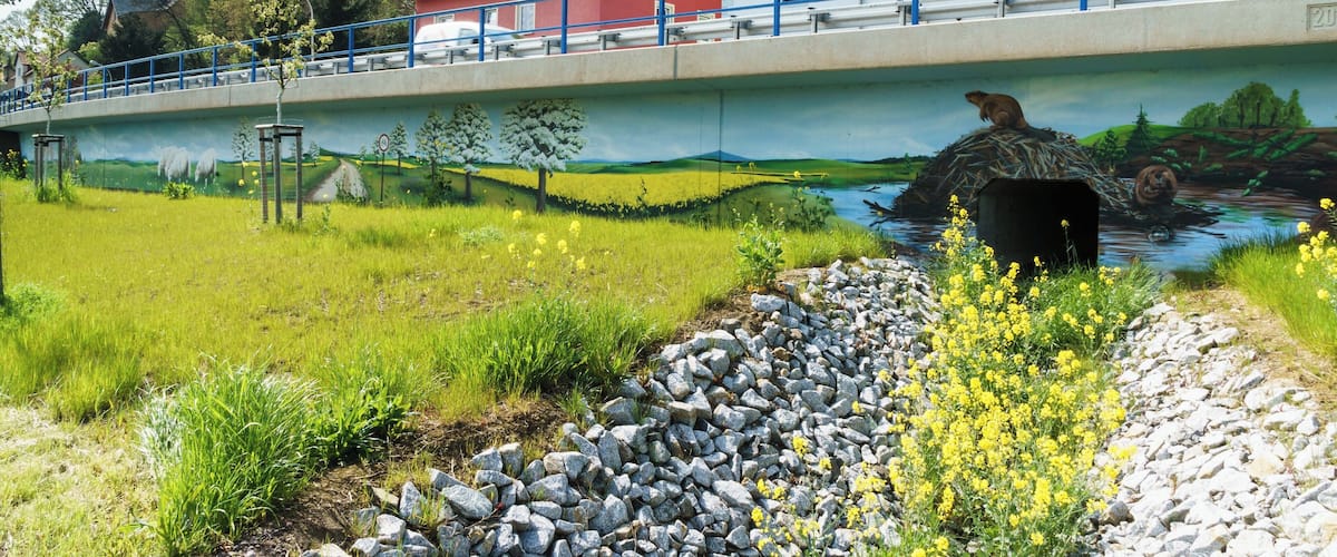 A bridge with a mural, a red house, and a white building.