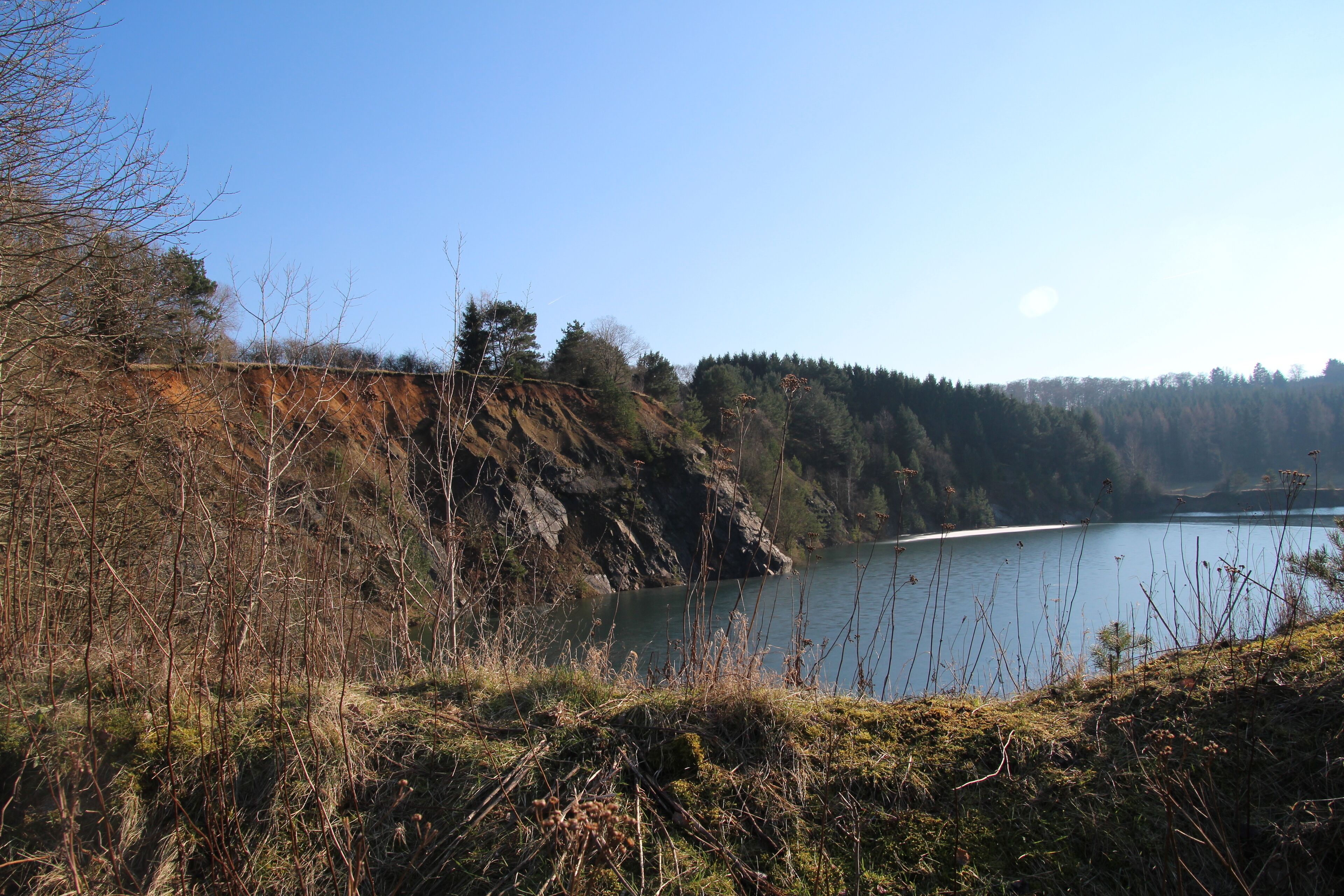 A lake surrounded by rocky cliffs and sparse vegetation.