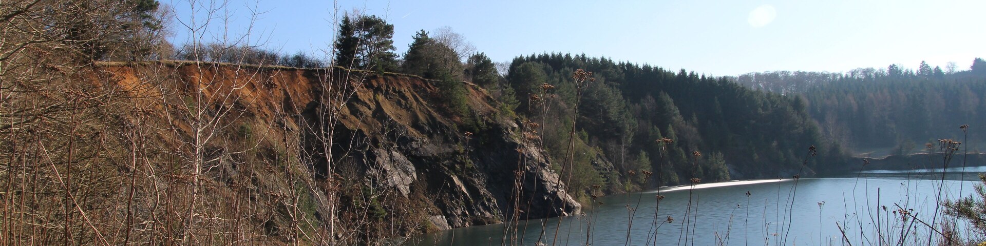 A lake surrounded by rocky cliffs and sparse vegetation.