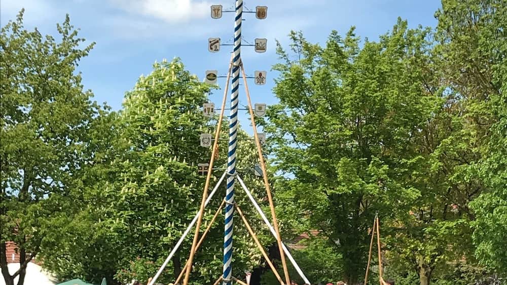 A tall, striped tower with flags at the top, surrounded by a crowd of people at an outdoor event.