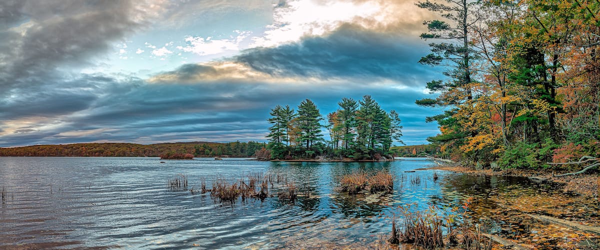 A calm lake surrounded by trees with autumn foliage.