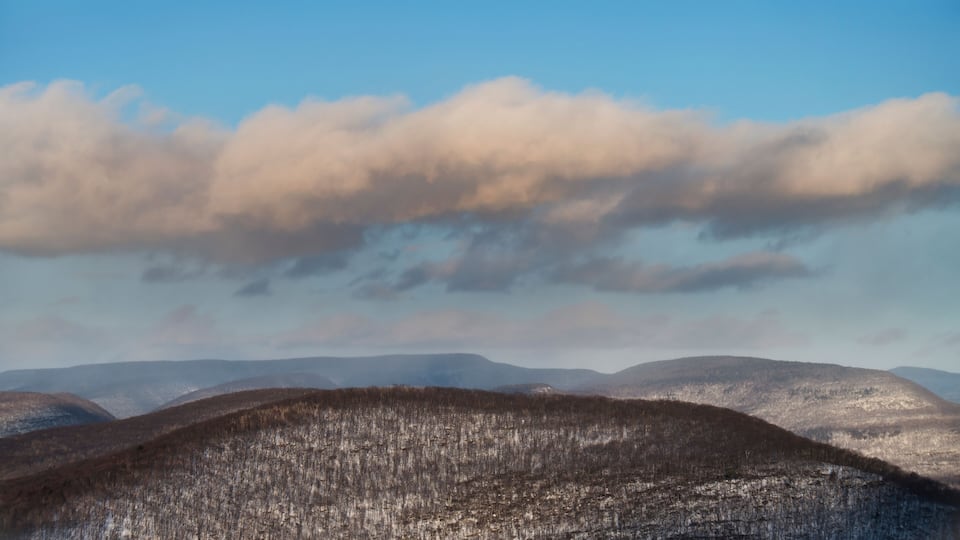 A mountainous landscape with a clear sky and fluffy clouds.