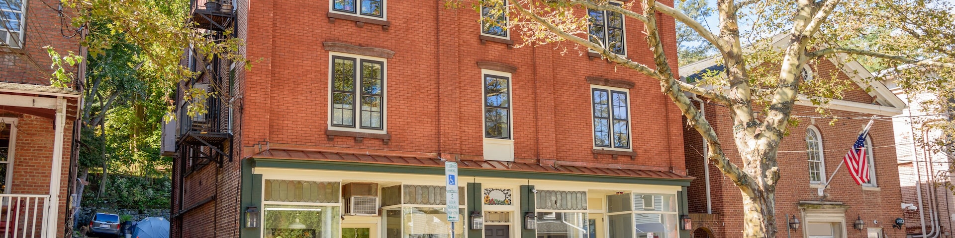 Traditional American brick buildings with shops on ground floor along a tree lined street in a historic downtown on a sunny autumn day